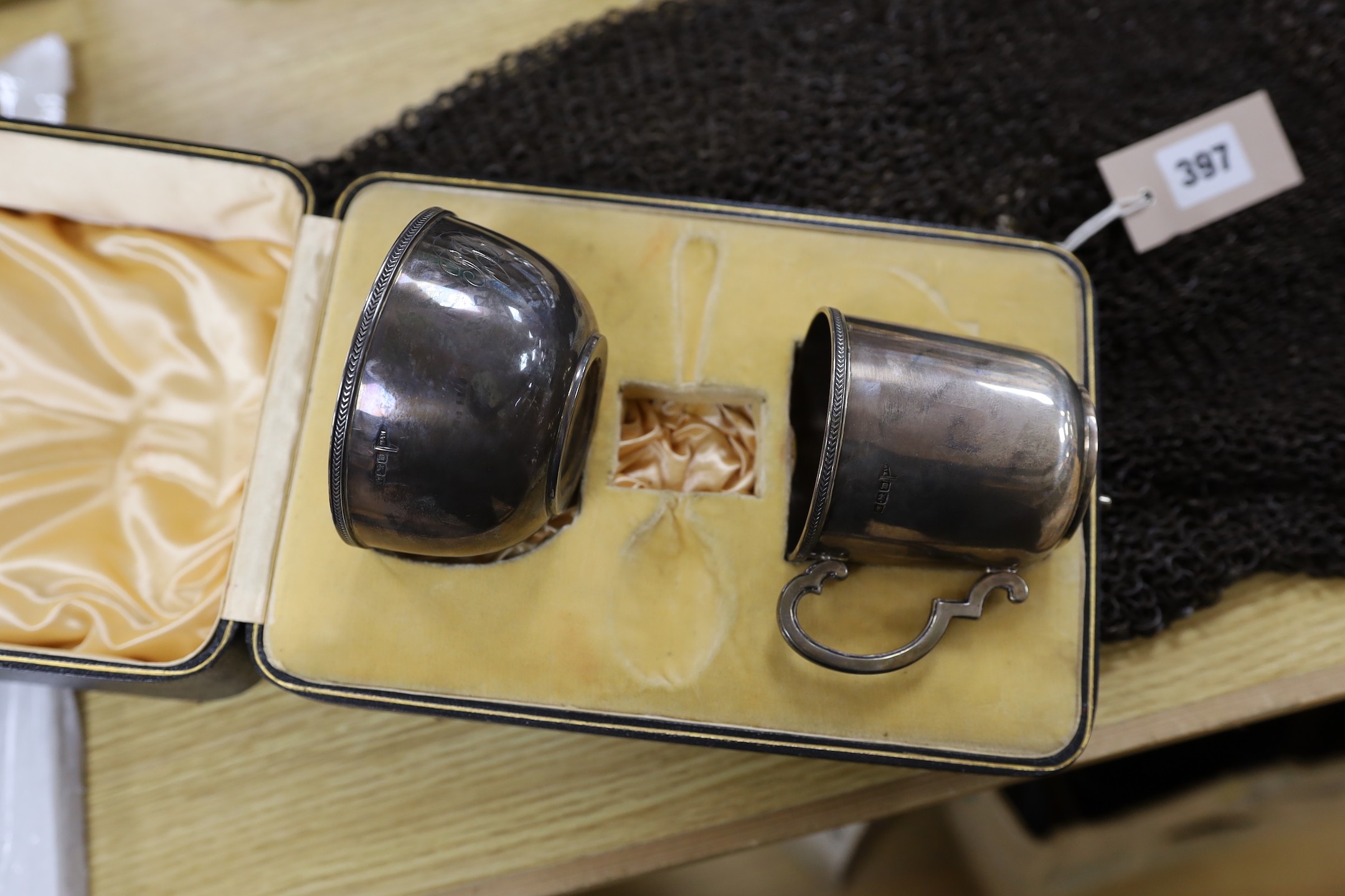 A George V silver capstan inkwell and a cased silver hair brush, two leather cased plate mounted glass flasks and tumbler sets, a George V cased silver christening bowl and mug set, a leather cased pair of silver hair br